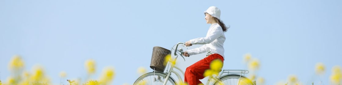 A young woman rides a bicycle through a summer field