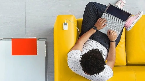 man sitting on a yellow sofa with laptop on his lap